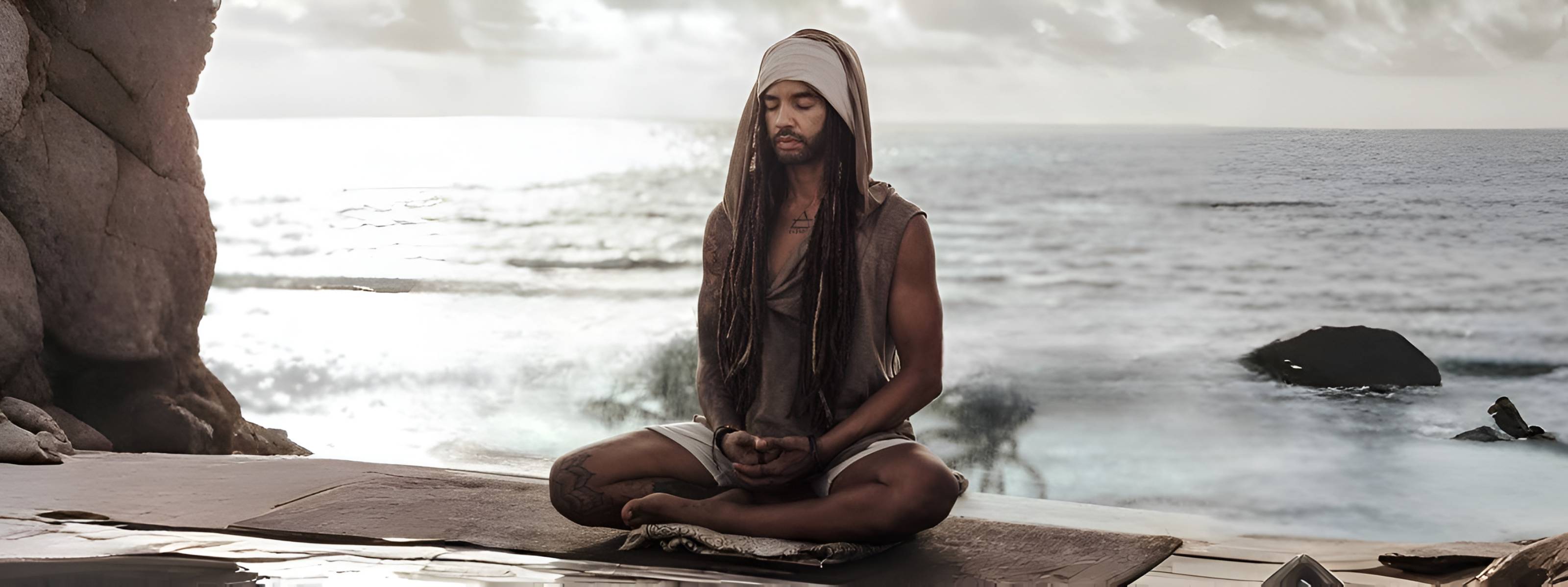 Person meditating on a wooden platform by the ocean
