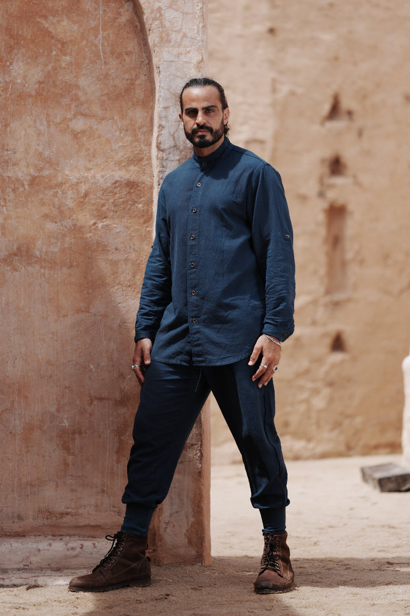Man standing in a sunlit stone archway in a blue linen suit