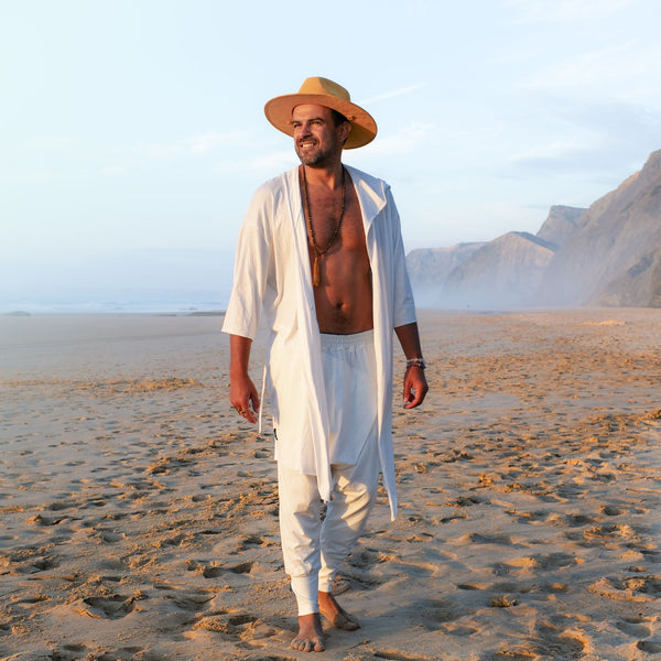 Man walking on a sandy beach with mountains in the background