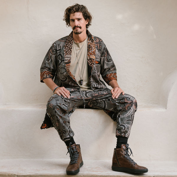 Man wearing a patterned outfit sitting on a white surface