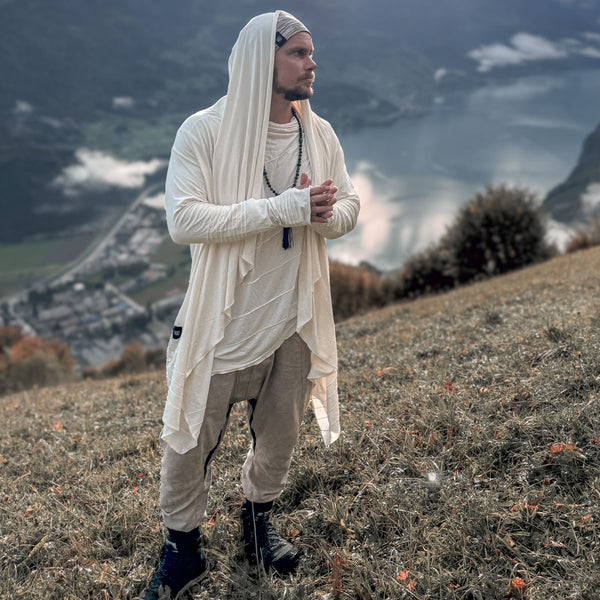 Person in white clothing standing on a hill with a scenic background