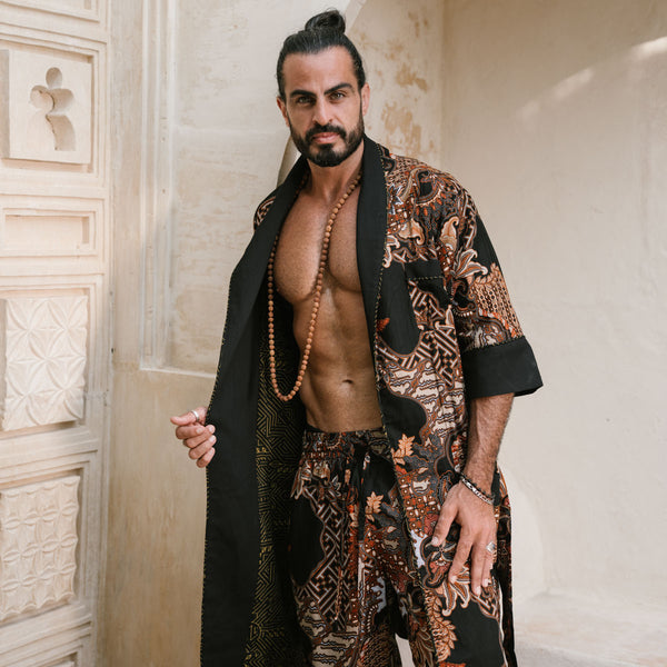 Man wearing a patterned robe and beads in an ornate setting