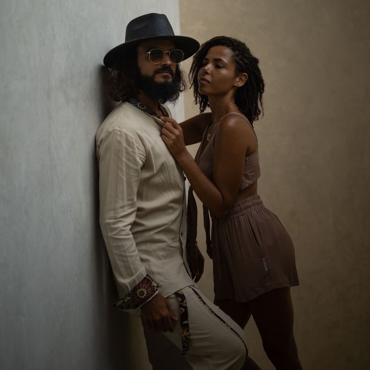Man and woman leaning against a wall with a neutral background